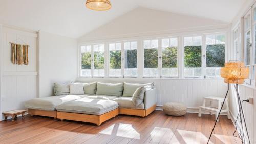 a living room with a couch and some windows at Welcome To Queenslander By The Sea in South Golden Beach