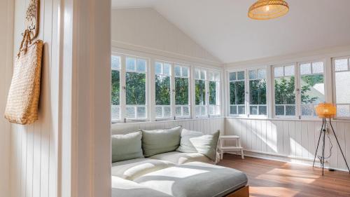 a living room with a white couch and windows at Welcome To Queenslander By The Sea in South Golden Beach