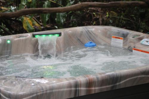 a hot tub with water in it with a waterfall at Halema'uma'u- Hale Kumu La'au in Volcano