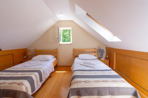 two beds in a attic room with a window at Villa Madunic with private swimming pool in Cista Provo