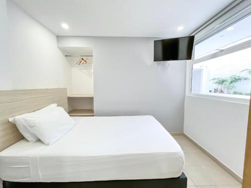 a bedroom with a white bed and a window at Stanza Hotel Monteria in Montería