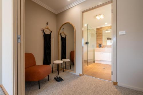 a hallway with a mirror and a chair and a bathroom at Hermitage Lodge in Pokolbin