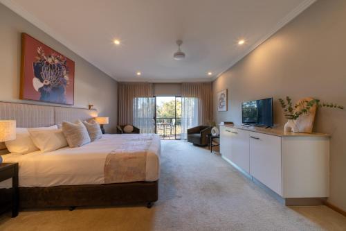 a bedroom with a large bed and a television at Hermitage Lodge in Pokolbin