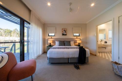 a large bedroom with a bed and a balcony at Hermitage Lodge in Pokolbin