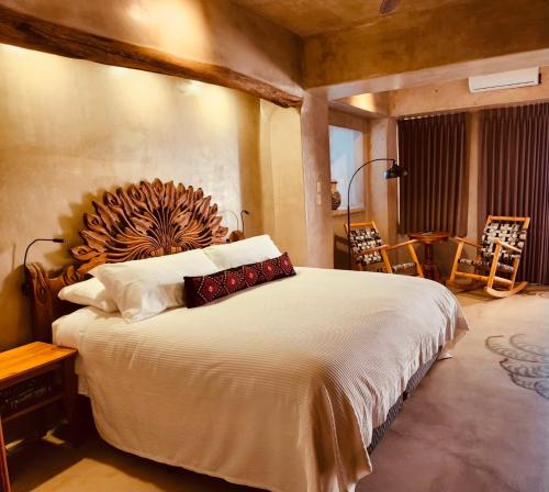 a bedroom with a large bed with a wooden headboard at Alegria Suites Centro Historico in Todos Santos