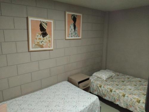 Zimmer mit 2 Betten und 2 Bildern an der Wand in der Unterkunft Casa alojamiento Ordoñez in Ilo