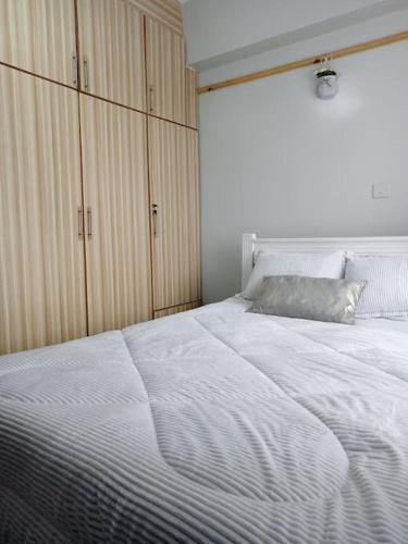 a bedroom with a large white bed with wooden cabinets at Golden Nest in Lake View Estate