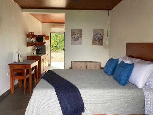 a bedroom with a bed with blue pillows and a desk at Villas Santa Maria - Private Bay Lake Arenal in Nuevo Arenal