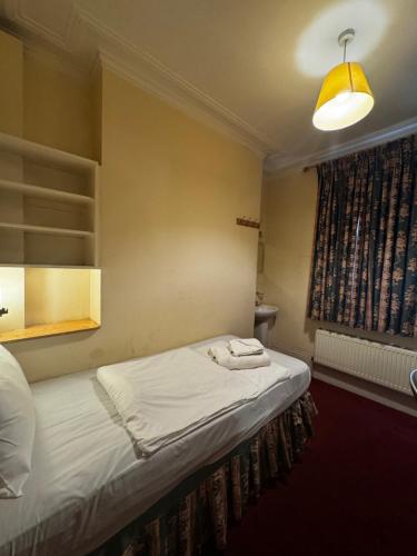 a bedroom with a bed with a lamp and a window at Bridge Park Hotel in London