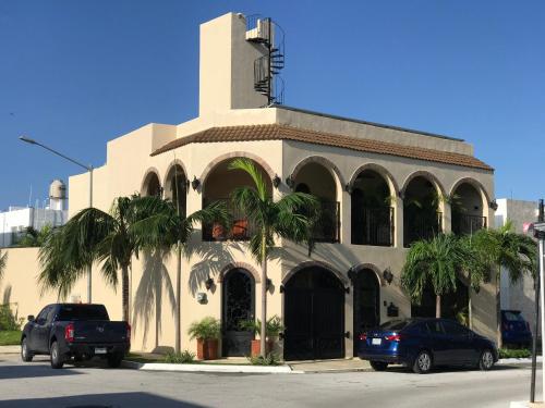 ein Gebäude mit zwei davor geparkten Autos in der Unterkunft Casa Castillo Playa in Playa del Carmen