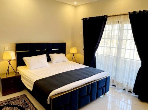 a bedroom with a large bed and a window at Riwayat Guest House in Islamabad