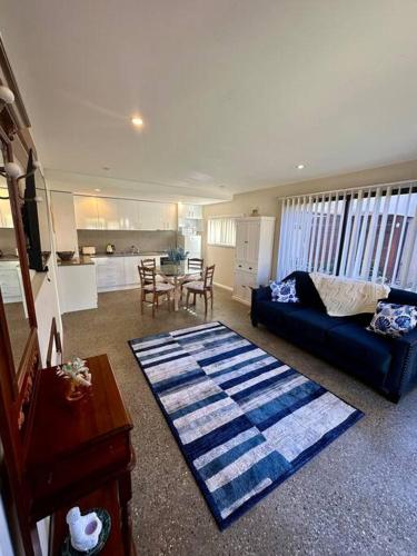 a living room with a blue couch and a table at Tasman Sea View Bonny Hills in Bonny Hills