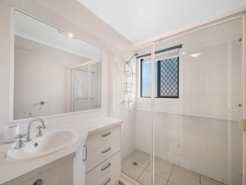 a white bathroom with a sink and a shower at 1 - 11 Roslin Street Moffat Beach QLD in Caloundra