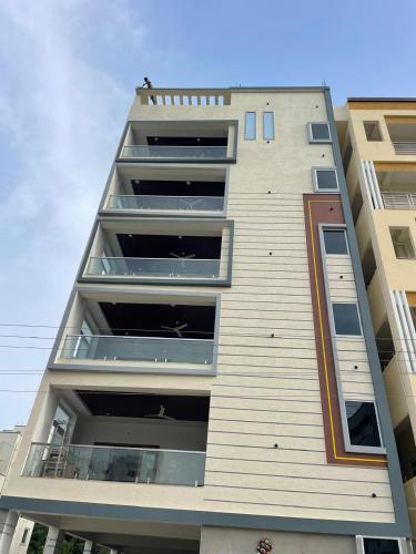 a tall apartment building with a man on the balcony at Nest Inn Homestay in Tirupati