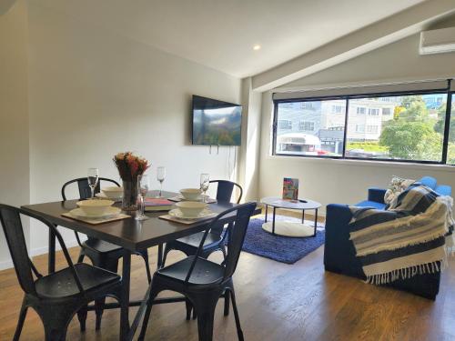 a dining room with a table and chairs in a living room at U Suites Kilbirnie in Wellington