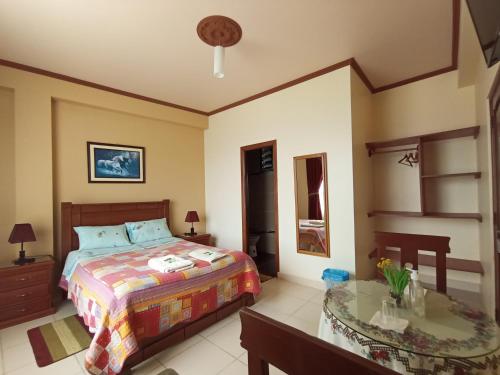 a bedroom with a bed and a table at Hostal Kurmi - Coroico in Coroico