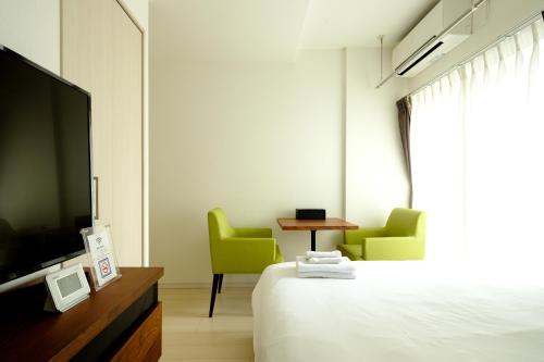 a hotel room with a bed and two chairs and a television at Live Casa Tokyo浜松町 - Direct Haneda Monorail - Near Tokyo Tower - 1 Stop to Shinkansen in Tokyo