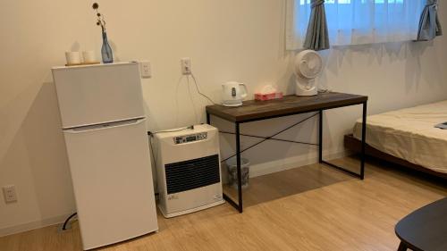 a room with a refrigerator and a table and a bed at 楽Home in Otaru