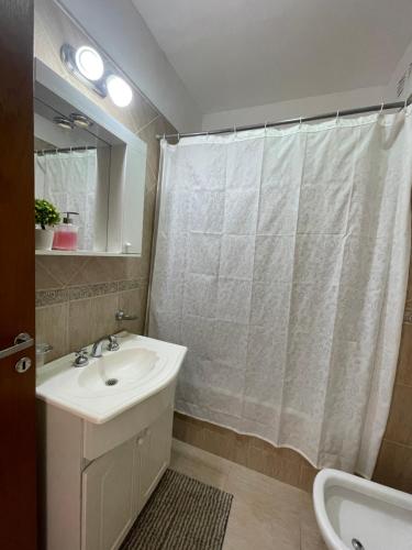 a bathroom with a sink and a shower curtain at Departamento Céntrico Resistencia in Resistencia