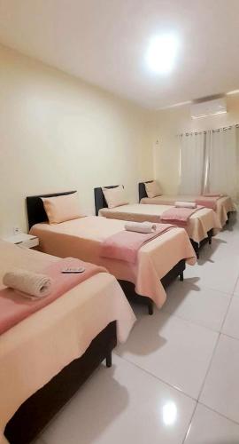 a row of beds in a room with pink sheets at DUNAS RESIDENCE CASA 14 in Santo Amaro