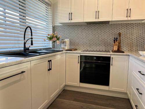 a kitchen with white cabinets and a black dishwasher at River Walk in Wynyard in Wynyard
