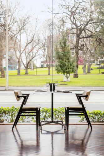 a white table with two chairs in front of a window at Radisson On Flagstaff Gardens Melbourne in Melbourne