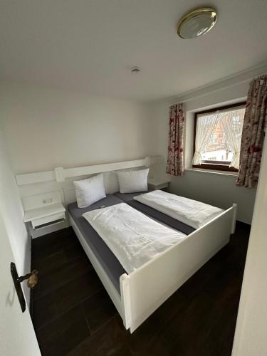 a bedroom with a white bed and a window at Gästehaus Deml in Berchtesgaden