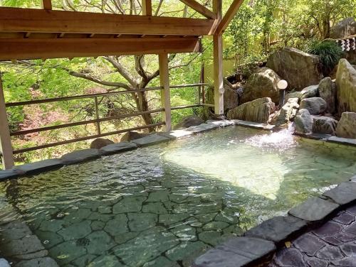 a pool of water in a backyard with a pergola at ハタラコリビングみなのsubako in Minano