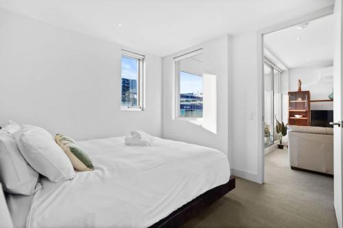 a white bedroom with a large bed and a mirror at W30 - Sparkling North Melbourne Gem with parking in Melbourne