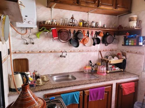 à 10 minutes du grand mall d'Afrique, WiFi Netflix 1ère étage في Oulad Hamida: مطبخ مع حوض وأواني ومقالي على الحائط