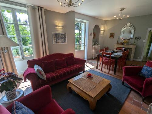 un salon avec des canapés rouges et une table dans l'établissement Maison XVIIIe avec jardin privatif - Yèvre le Châtel - FR-1-590-440, à Yèvre-la-Ville