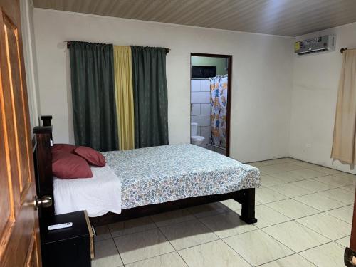 a bedroom with a bed and a window with curtains at Coconut Casa 10 Min from La Fortuna with AC - Fast Wi-Fi - Private Parking in a Friendly Neighborhood in Fortuna