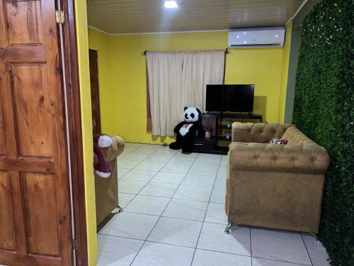 a panda bear sitting in a room with a tv at Coconut Casa 10 Min from La Fortuna with AC - Fast Wi-Fi - Private Parking in a Friendly Neighborhood in Fortuna