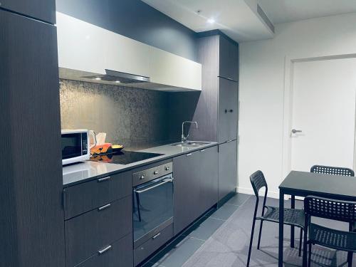 a kitchen with gray cabinets and a table with chairs at Southbank Hidden Gem in Melbourne