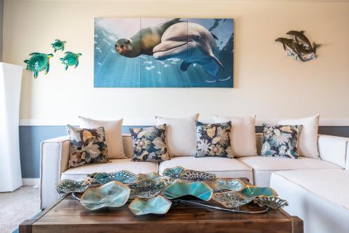a living room with a couch with a dolphin painting on the wall at Newly Remodeled Family Friendly Ocean View - Oceanic Mirage in Newport