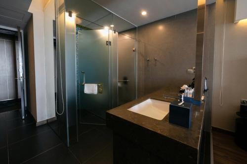 a bathroom with a sink and a glass shower at Novotel Suites Hanoi in Hanoi