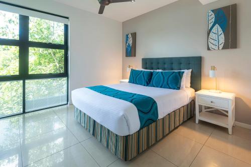 a bedroom with a large bed with blue pillows at Edge Apartments on Hamilton Island by HIHA in Hamilton Island