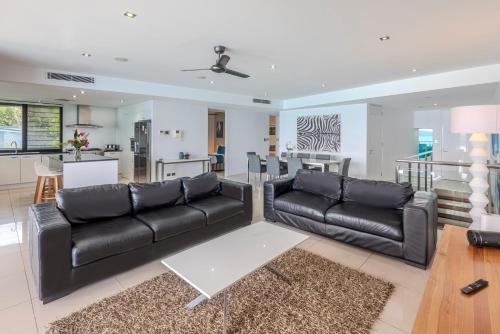a living room with a black leather couch and a table at Edge Apartments on Hamilton Island by HIHA in Hamilton Island