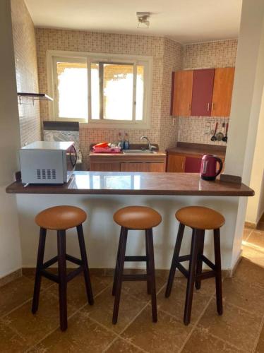 a kitchen with two bar stools and a counter top at Blumar El sokhna in Al Ḩafāʼir