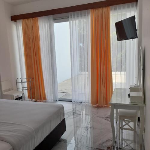 a bedroom with a bed and a desk and a television at Beach Hotel Wirton Batukaras in Batukaras