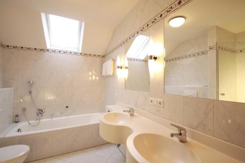 a white bathroom with a sink and a tub and a mirror at Hotel Hirsch in Kehl am Rhein