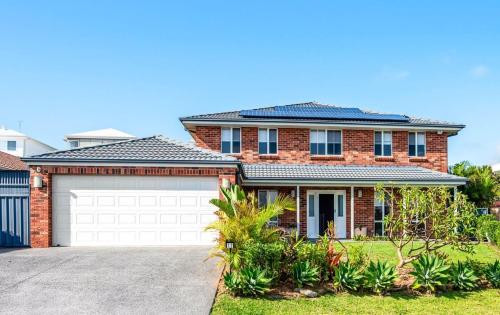 a brick house with a garage at Cheerful 4-bedroom family retreat in Caves Beach in Caves Beach