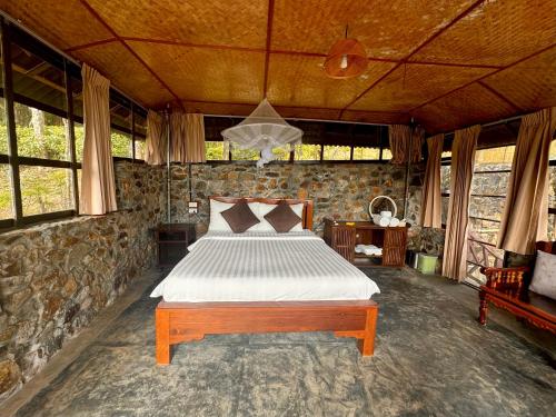 a bedroom with a bed in a stone wall at Drifters Anchor in Ban Map Khangkhao