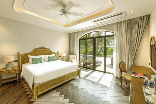 a bedroom with a bed with a ceiling fan at Sunset Sanato Resort & Villas in Phu Quoc