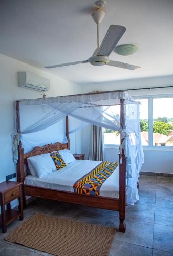 a bedroom with a canopy bed with a fan at Wendy's Penthouse Diani in Ukunda