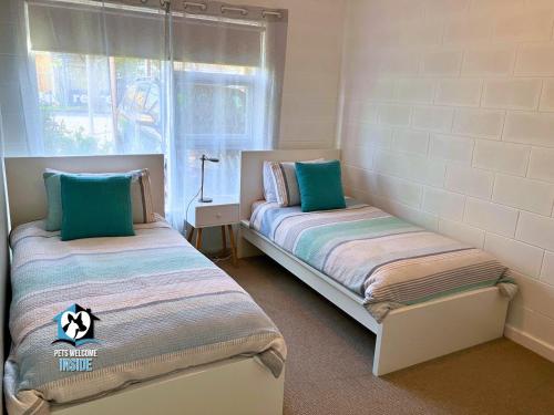 two beds in a small room with a window at Renovated 3BR One Street to Beach in Victor Harbor