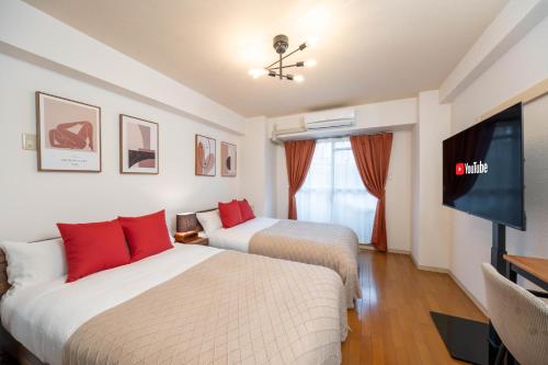 a hotel room with two beds and a flat screen tv at Nakatsu Sakae Manshon in Osaka