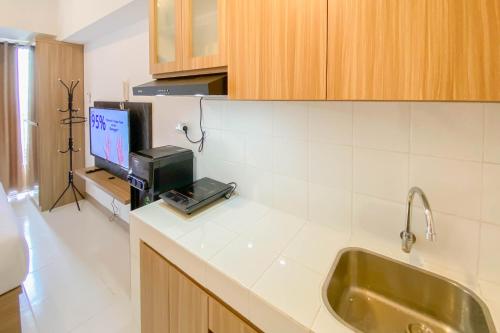 RawalembangRelaxing and Cozy Studio Tokyo Riverside PIK 2 Apartment By Travelio的一个带水槽的厨房和一台台面上的电视