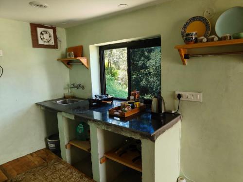 a kitchen with a counter with a sink and a window at Astitva Binsar in Hawālbāgh