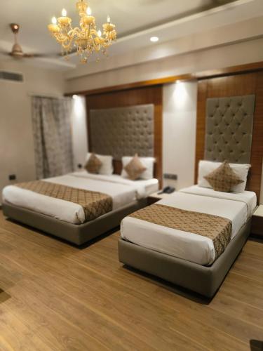 two beds in a hotel room with a chandelier at Hotel The Pearl, City Center - Traveler's Choice Award Winner for 2025 in New Delhi